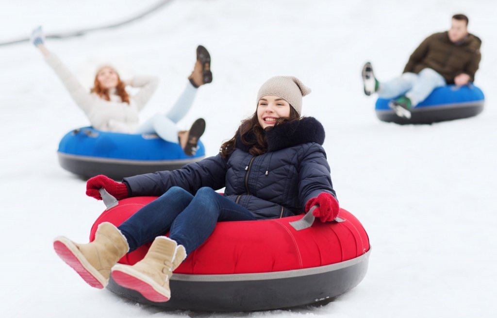 group of friend tubing on snow down hill