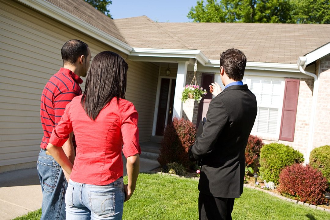 Real estate agent showing couple the front of a house